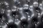 Close-up of black leather chesterfield sofa tufted upholstery texture