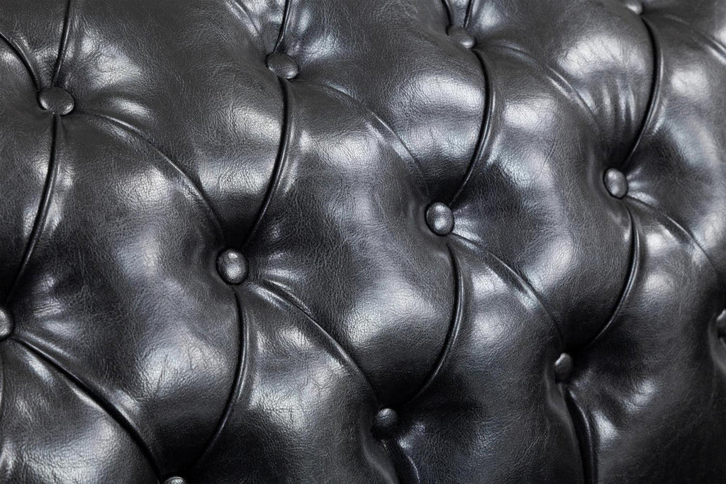 Close-up of black Chesterfield leather sofa with deep button tufting