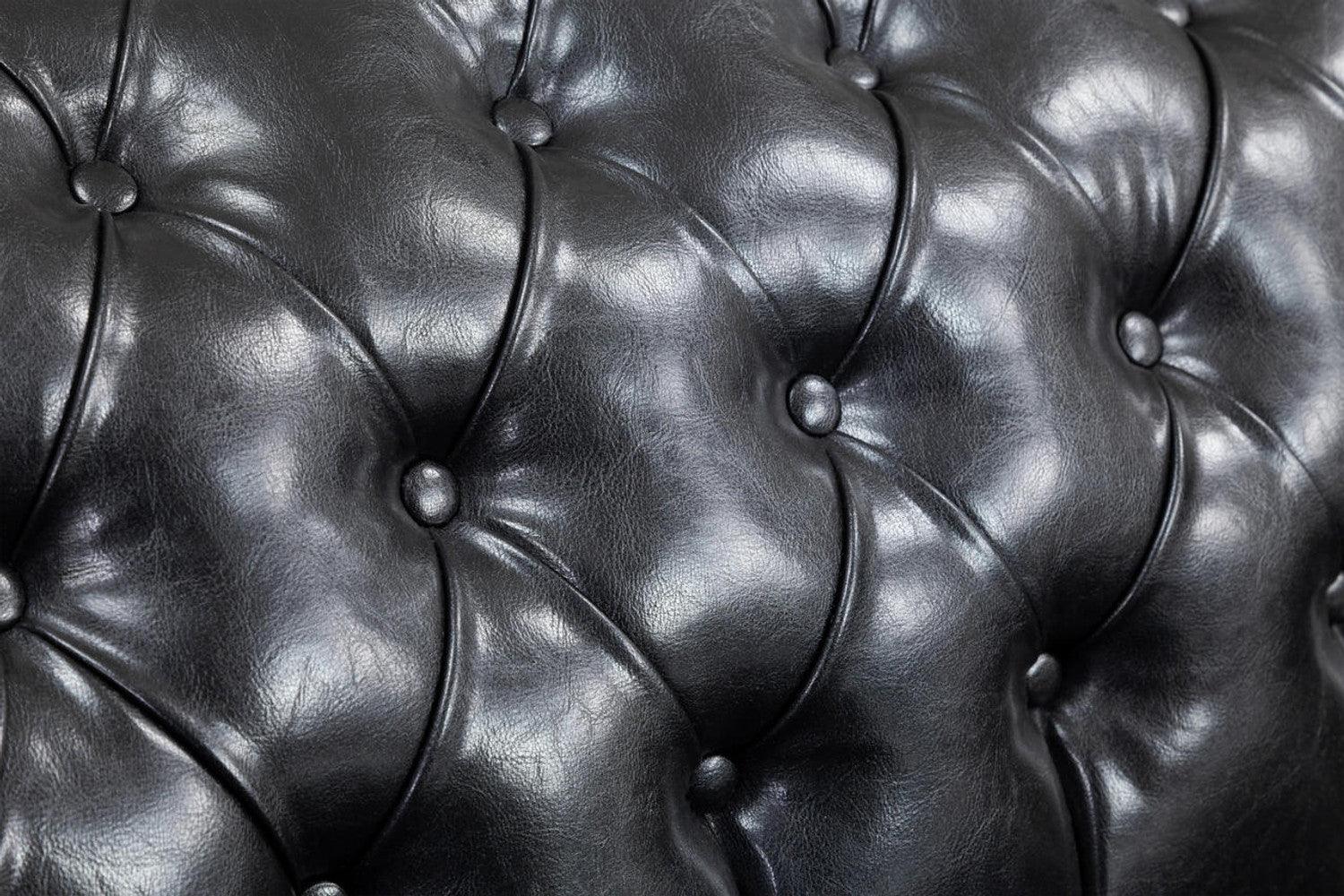 Close-up of black Chesterfield leather sofa with deep button tufting