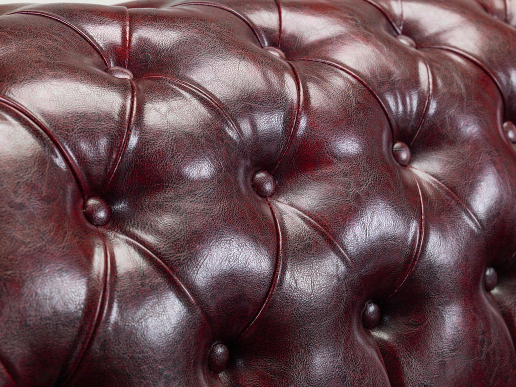 Close-up of a tufted oxblood chesterfield leather sofa backrest