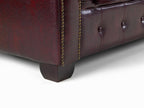 Close-up of oxblood leather Chesterfield sofa with tufted design and brass nailhead trim