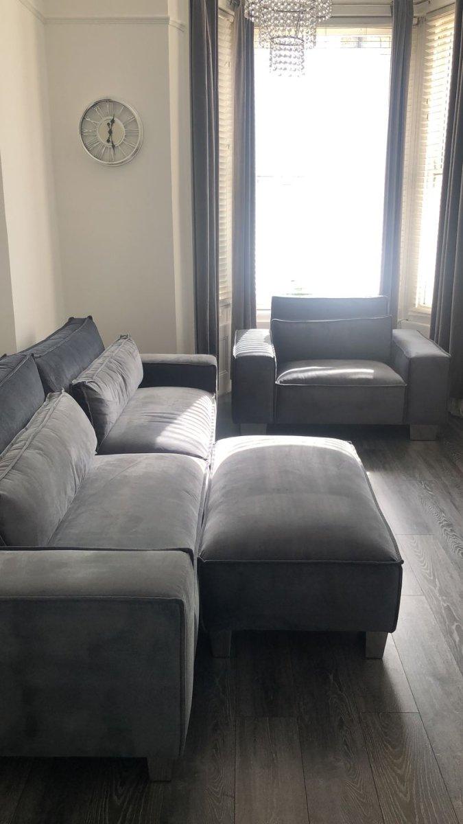 Grey velvet sofa set with armchair and ottoman in modern living room with wood floors