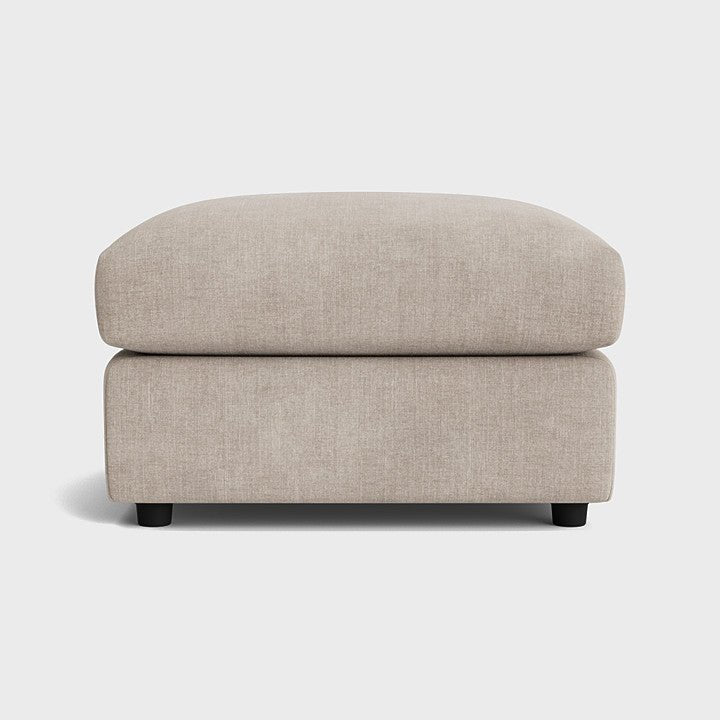 Modern cream fabric ottoman footstool with minimalist design on a white background