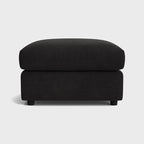 Modern black fabric ottoman with soft cushioning on a plain background