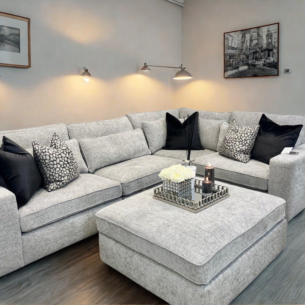 Modern ash grey corner sofa set with ottoman, black and patterned cushions in stylish living room