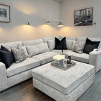 Modern ash grey corner sofa set with ottoman, black and patterned cushions in stylish living room
