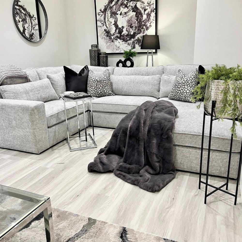 4-piece ash grey corner sofa in modern living room with cushions and faux fur throw