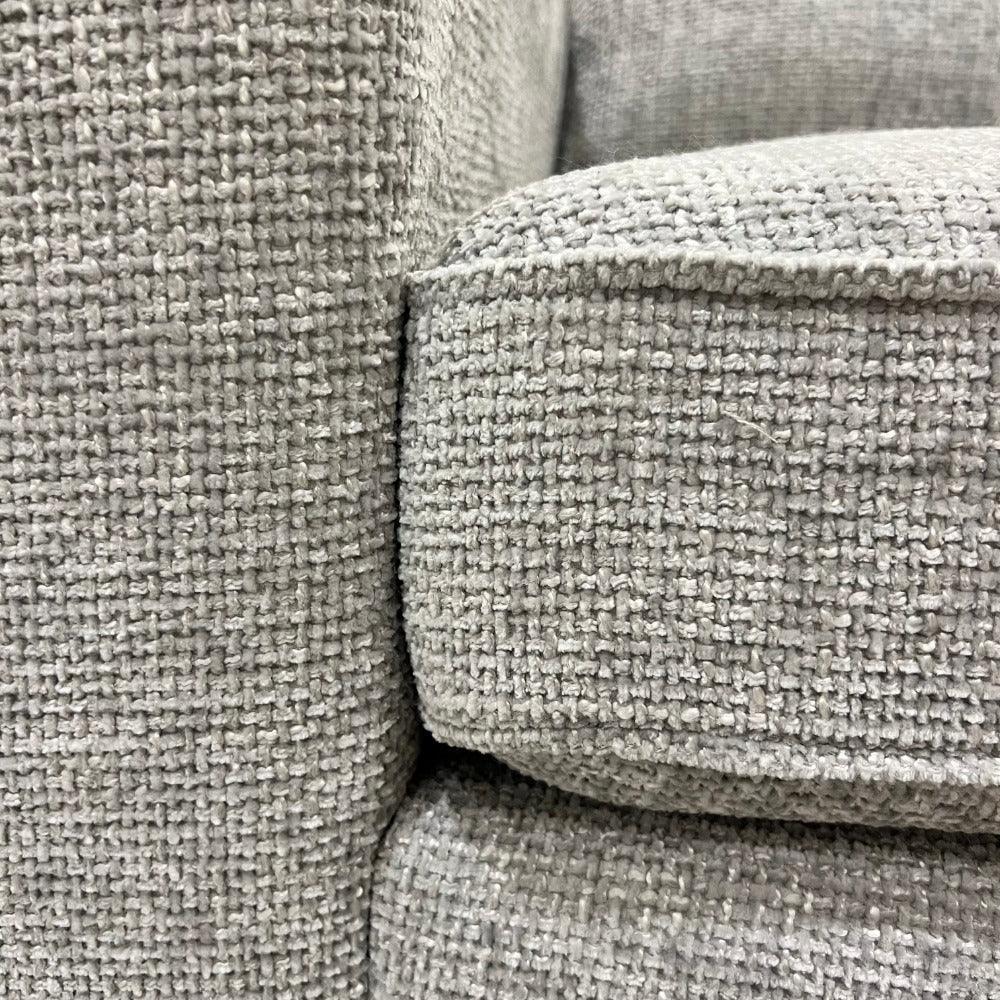 Close-up of ash grey textured fabric on a modern corner sofa cushion