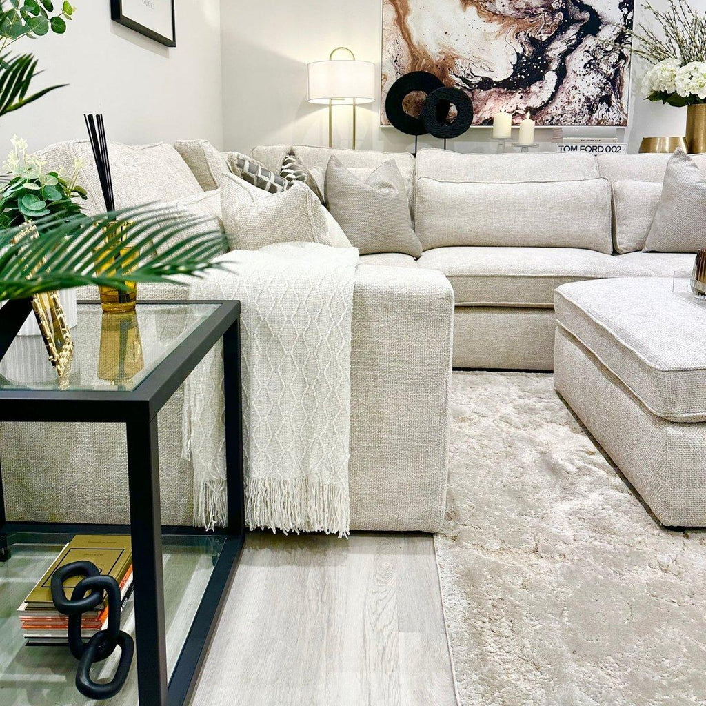 Modern living room with oatmeal corner sofa, neutral decor, and glass side table