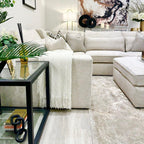Modern living room with oatmeal corner sofa, neutral decor, and glass side table