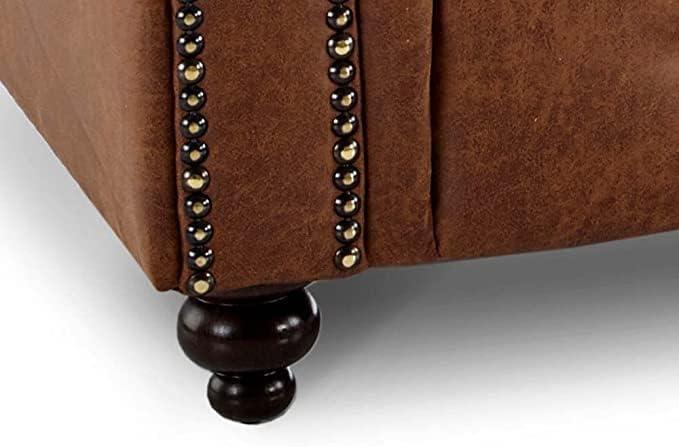 Detail of brown upholstered sofa corner with decorative nailhead trim and dark wood leg