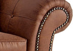 Close-up of brown leather sofa armrest with decorative nailhead trim and tufted detail