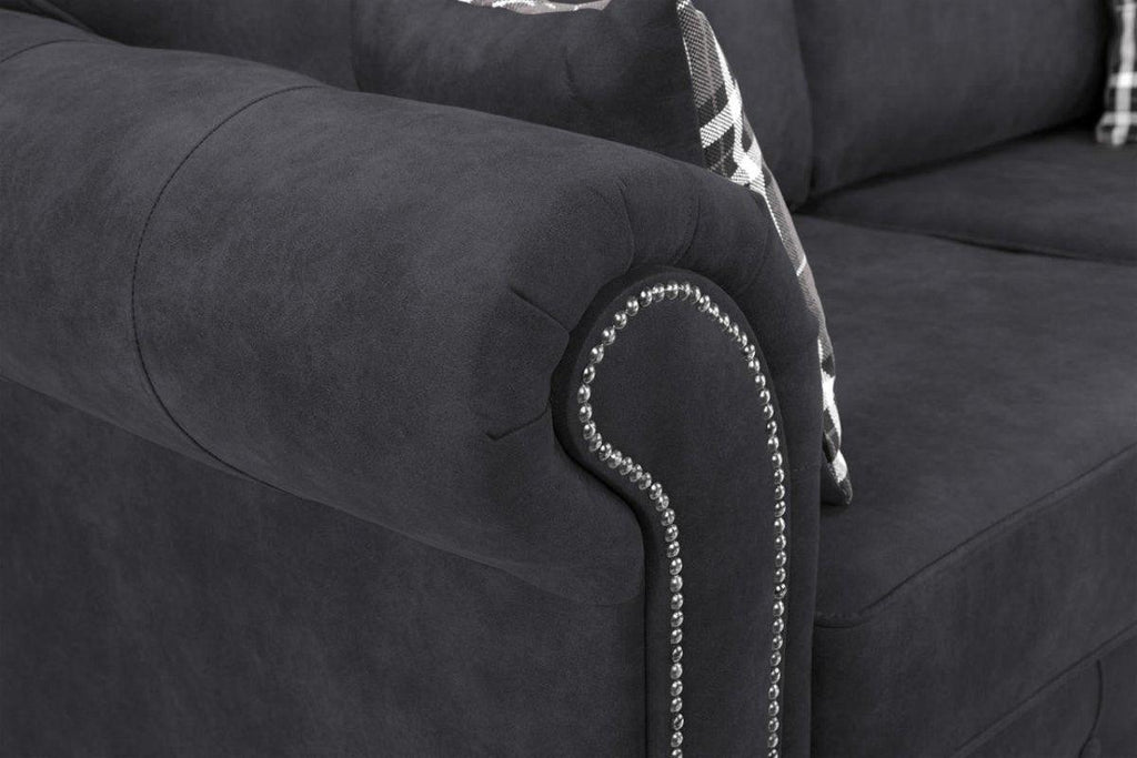 Black fabric sofa with rolled armrest, silver stud detailing, and plaid cushions