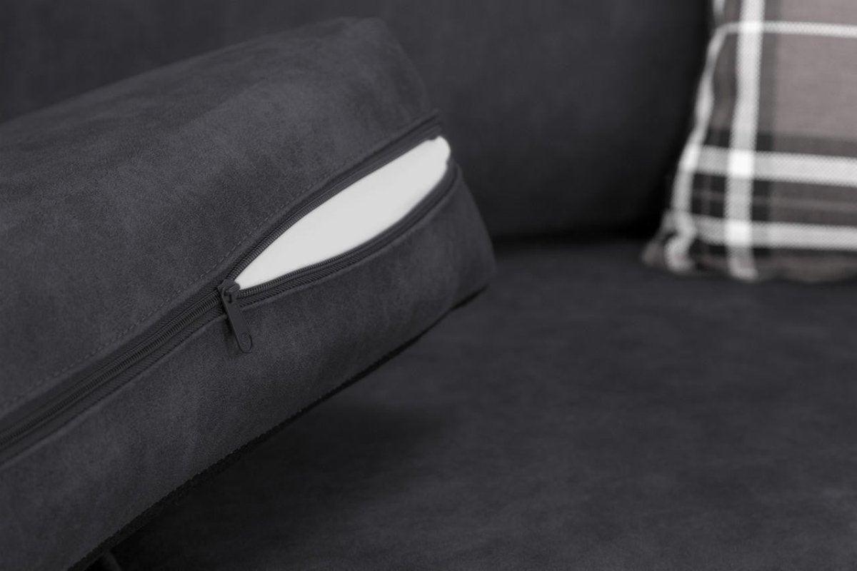 Close-up of a black sofa cushion with a visible zipper and plaid accent pillow