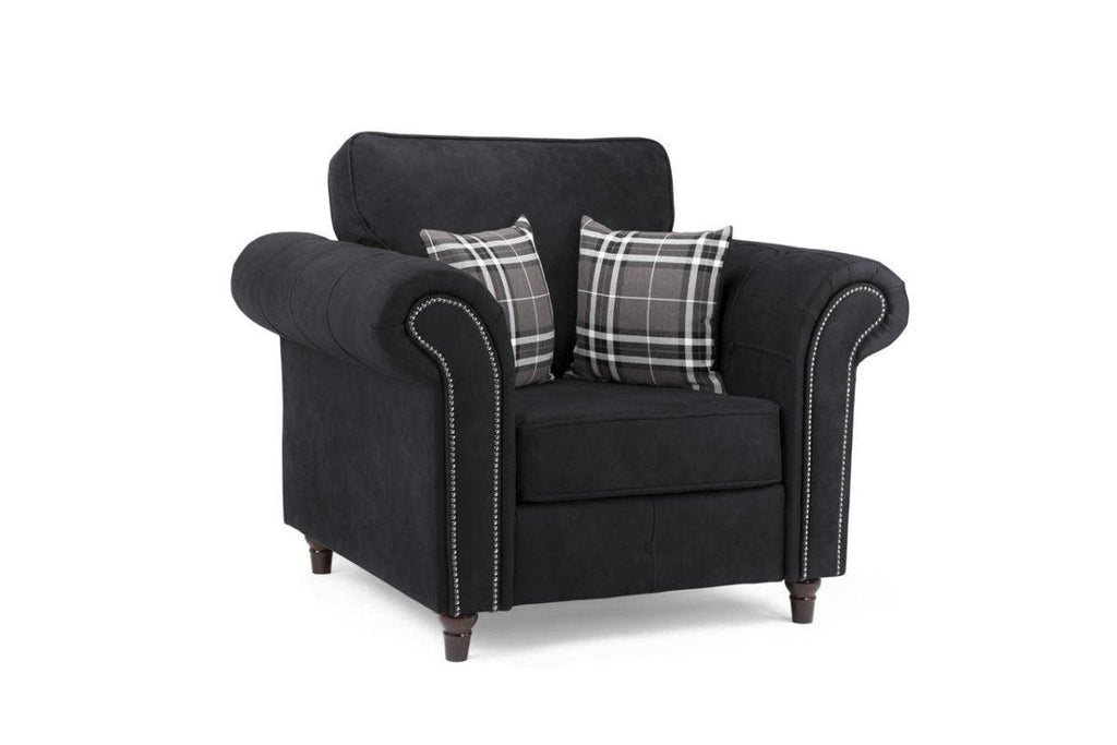 Black one-seater armchair with plaid accent pillows and studded rolled arms on white background