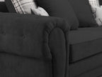 Close-up of black fabric sofa with plush cushions and plaid accent pillows
