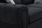 Close-up of black three-seater sofabed with plush cushions and button detailing.