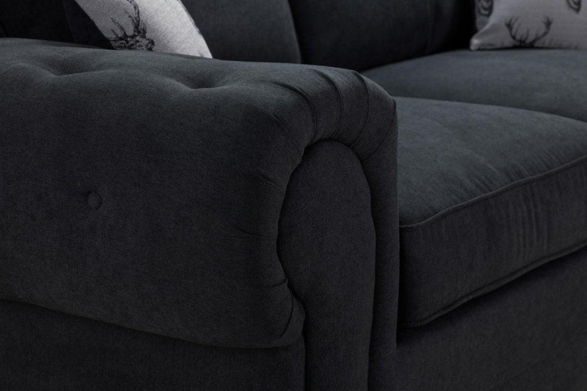 Close-up of black three-seater sofabed with plush cushions and button detailing.