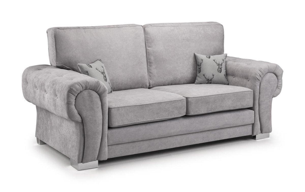Light grey three-seater sofa with tufted arms and two patterned accent cushions