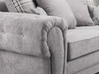 Close-up of grey scatterback sofa with button detailing and plaid accent cushions