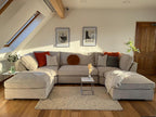 Large cream boucle U-shape sofa in modern living room with cushions and throw blanket