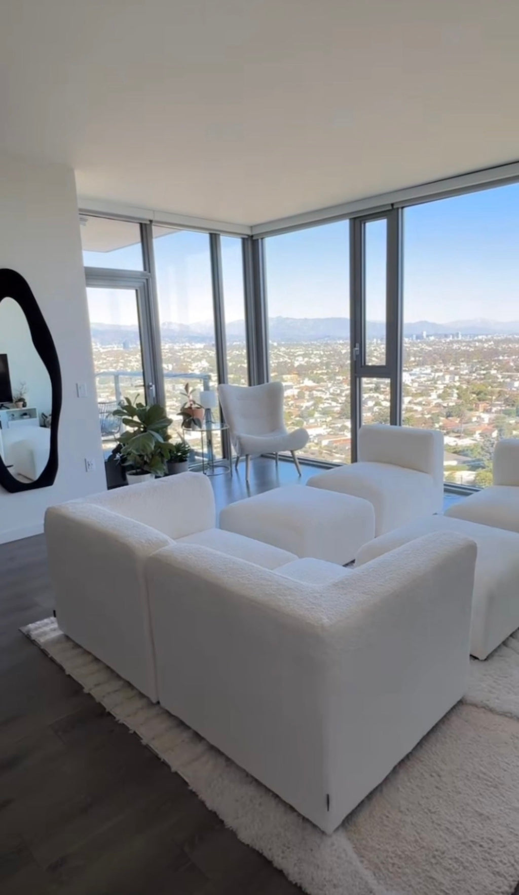 Cream boucle modular U-shape sofa with footstools in a modern living room with city views
