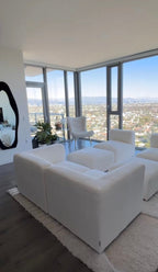 Cream boucle modular U-shape sofa with footstools in a modern living room with city views