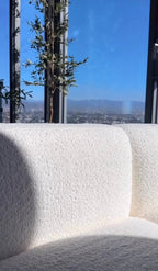 Cream boucle sofa in modern living room with large windows and city skyline view