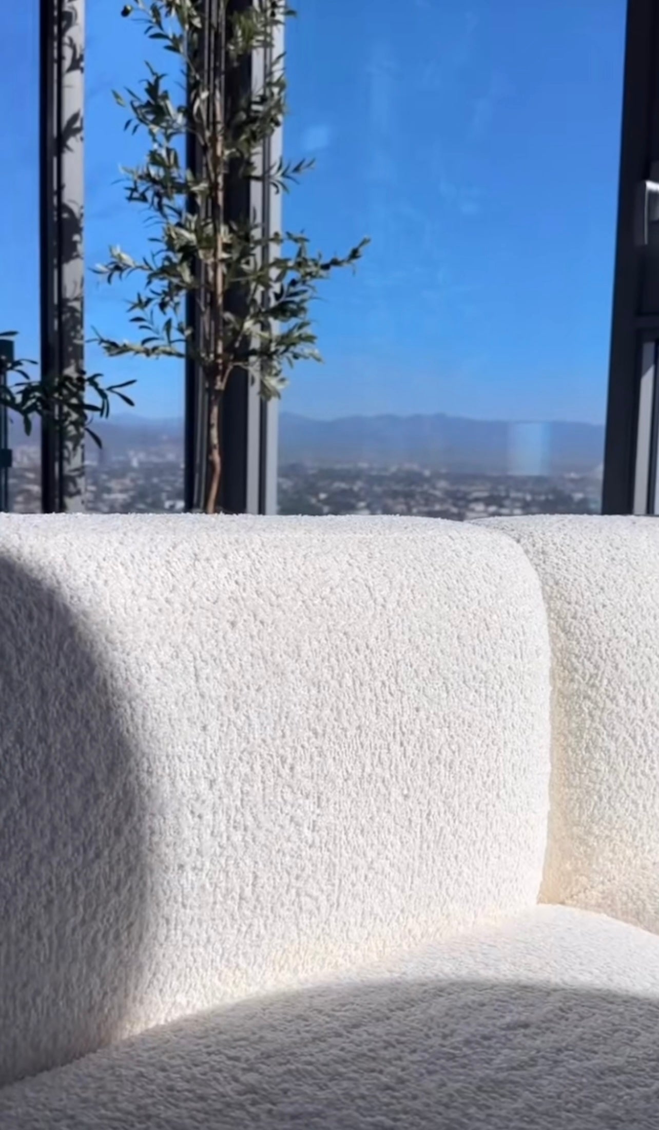 Cream boucle sofa in modern living room with large windows and city skyline view