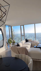 Cream boucle U-shaped modular sofa in bright modern living room with large windows and plants