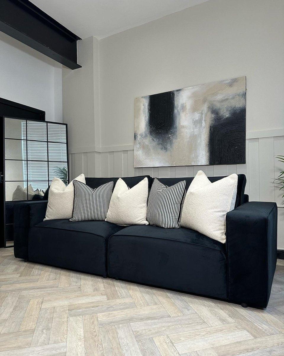 Modern black four-seater sofa with cream and striped cushions in a stylish living room