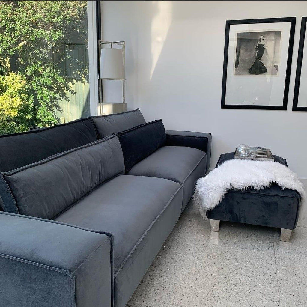 Modern large grey 4-seater sofa with matching ottoman in a bright living room