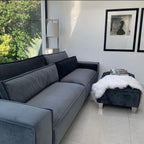 Modern large grey 4-seater sofa with matching ottoman in a bright living room