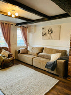 Large cream 4-seater sofa in cozy living room with cushions and modern decor