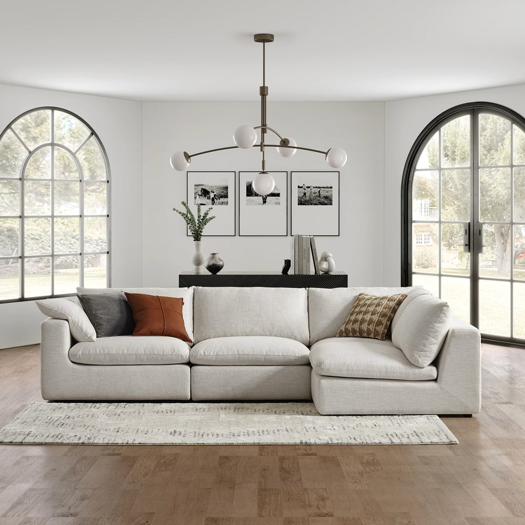 Cream feather-filled corner sofa in a modern living room with large windows and minimalist decor.
