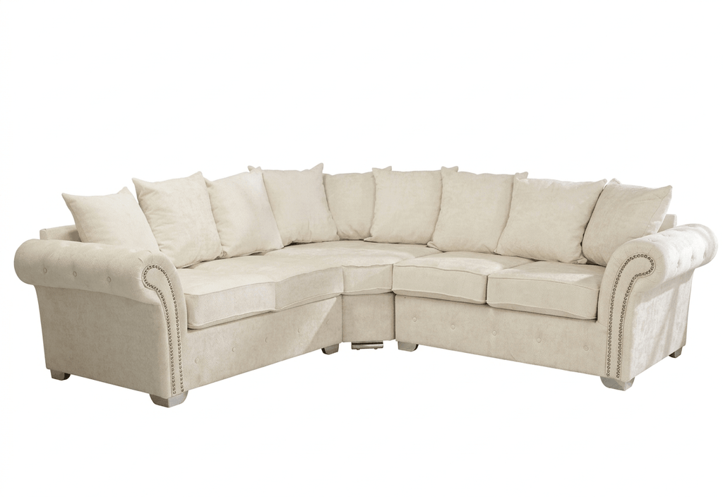 Cream corner sofa with full back cushions and studded rolled arms on white background