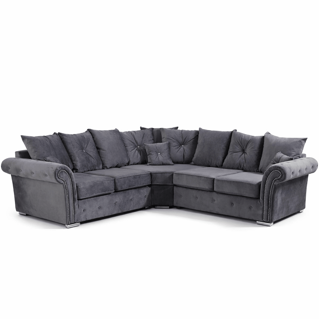 Grey velvet corner sofa with scatterback cushions and studded armrests