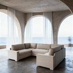 Cream U-shaped sectional sofa in modern room with arched windows and sea view