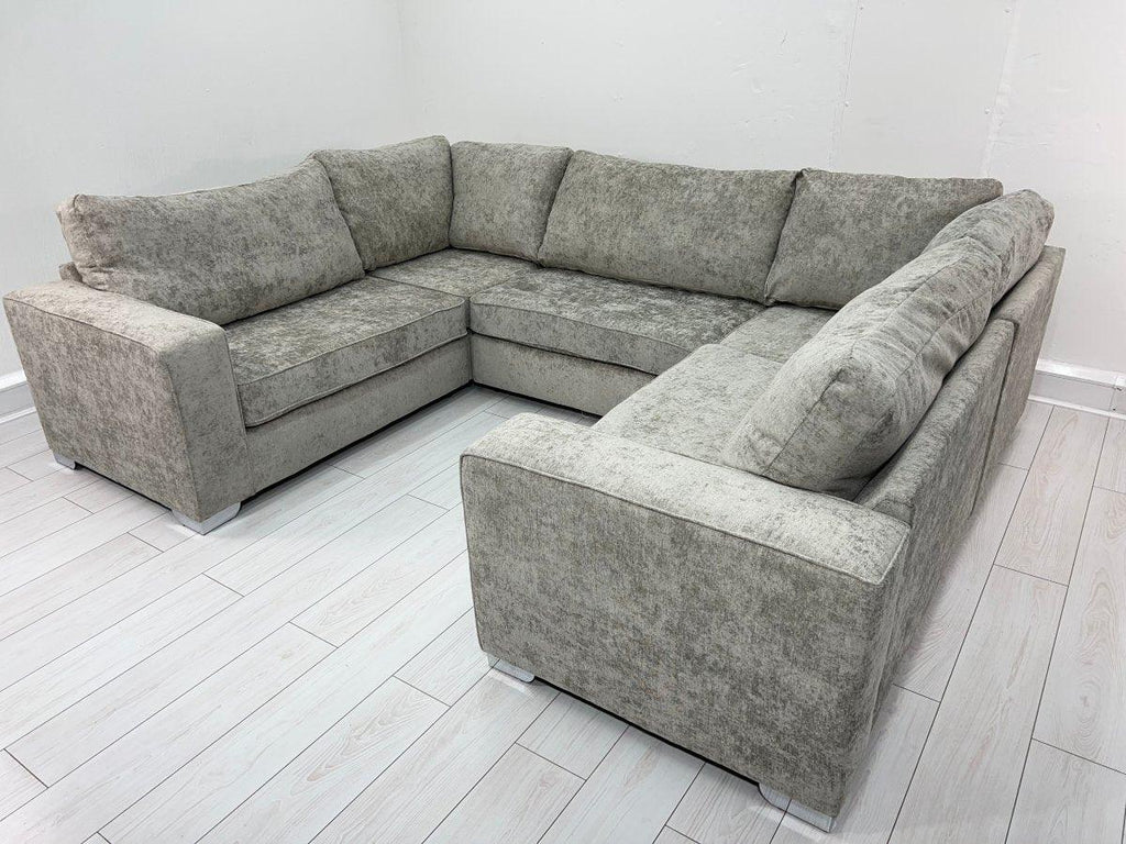 Modern grey U-shaped sofa with plush cushions in a bright room with light wood flooring