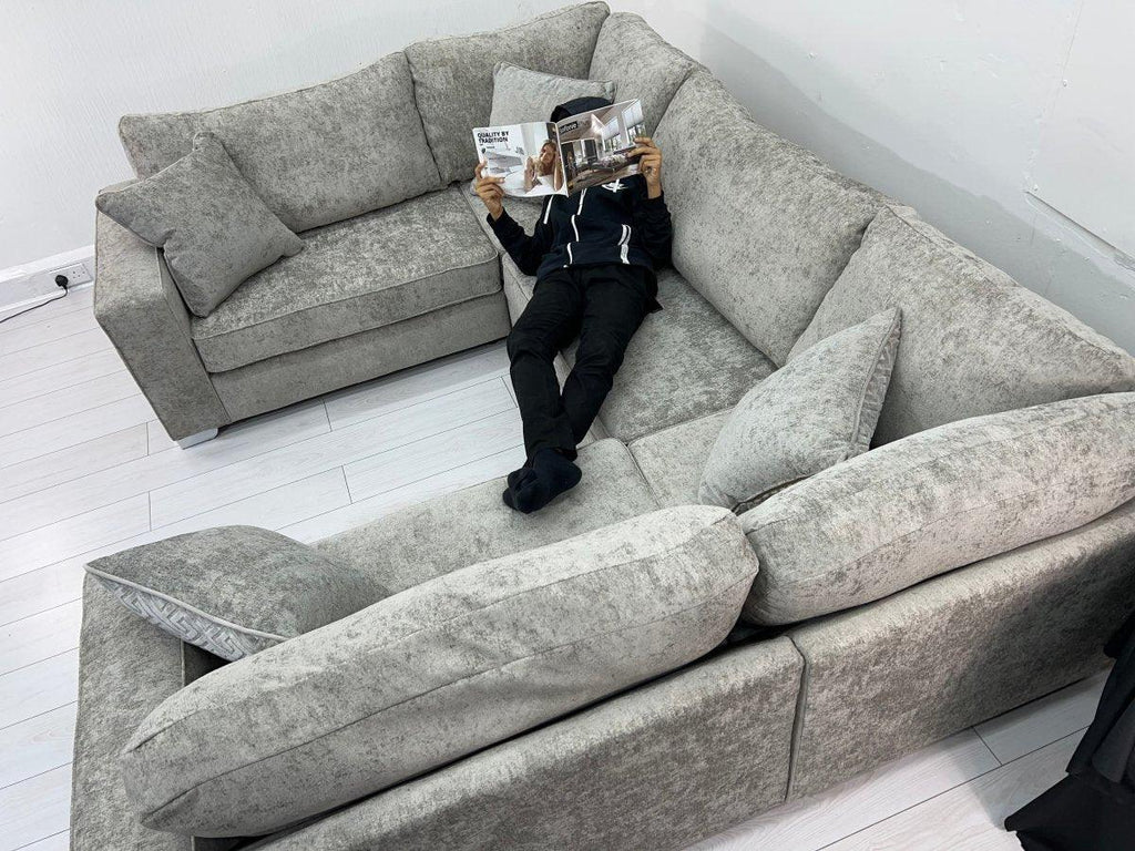 Modern U-shaped grey fabric sofa in white living room with person reading a magazine