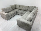 Modern U-shaped grey fabric sofa with plush cushions in a minimal light room