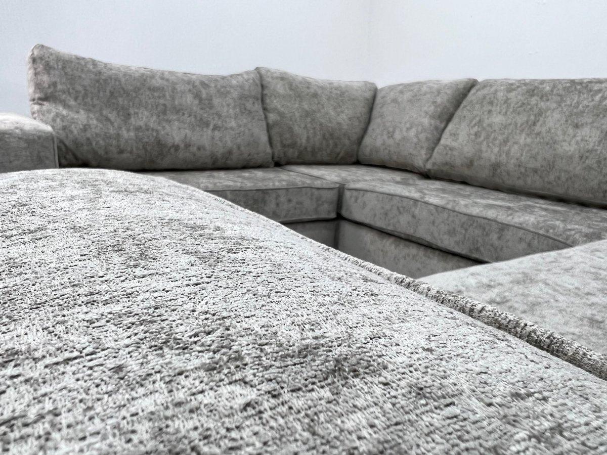 Modern U-shape grey corner sofa with plush fabric upholstery in a bright living space