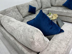 Modern U-shaped grey sofa with blue velvet cushions and a gold tray on a black table