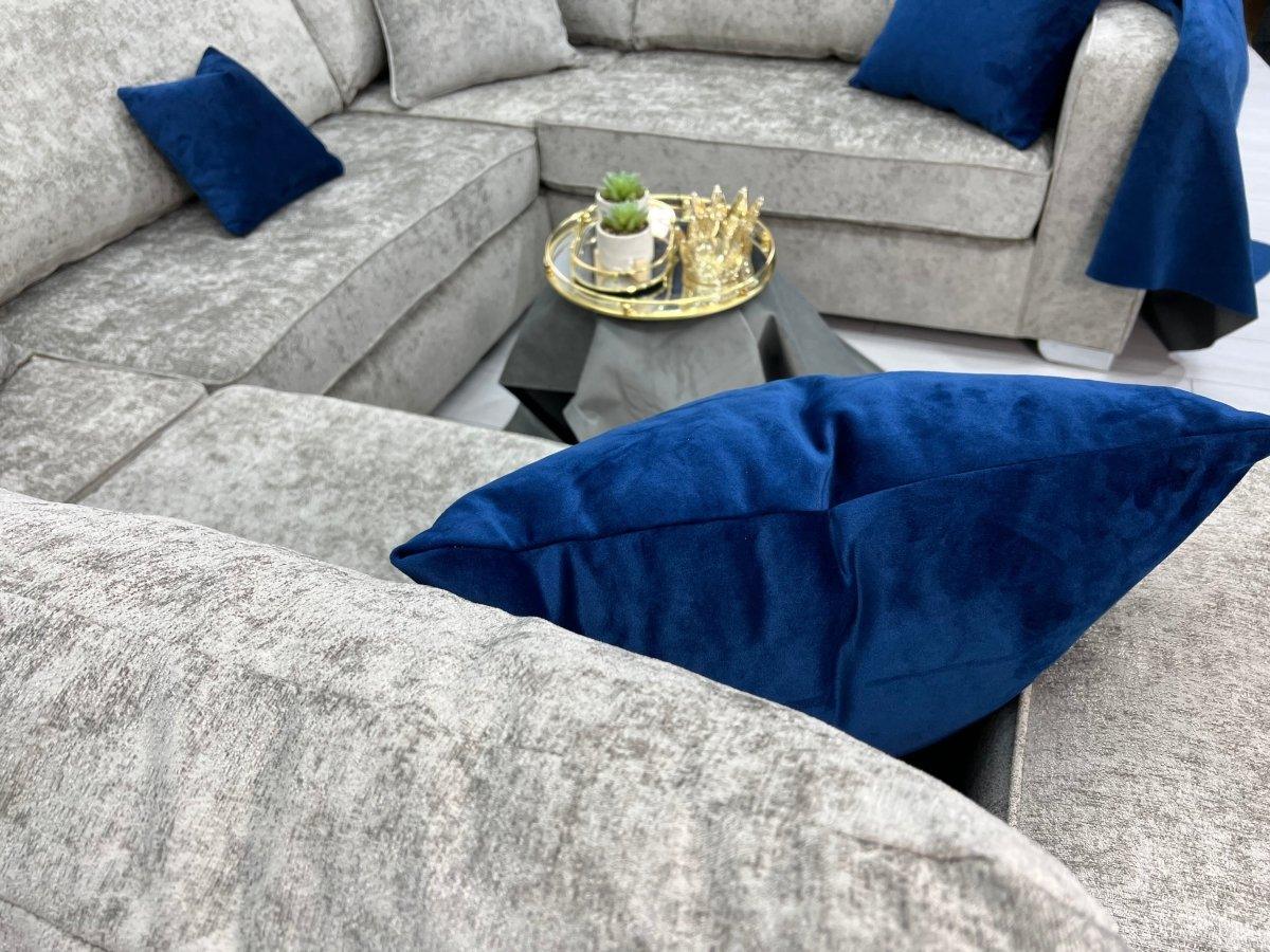 Modern U-shape grey sofa with blue velvet cushions and coffee table decor