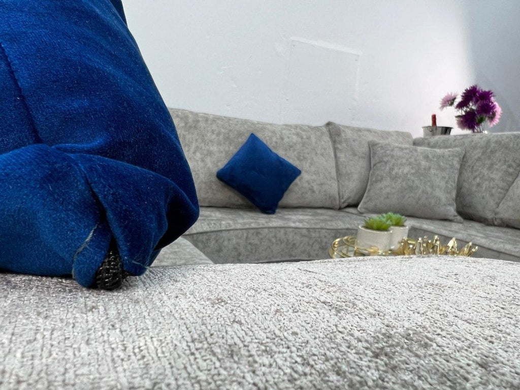 Contemporary light grey U-shaped sofa with blue accent pillows and a gold coffee table