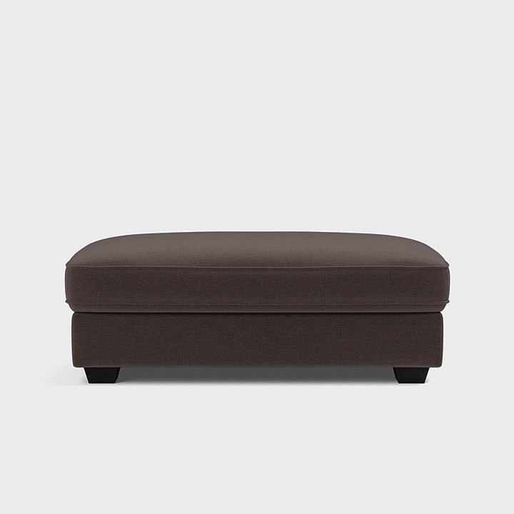 Modern double espresso brown fabric footstool with short legs on plain background