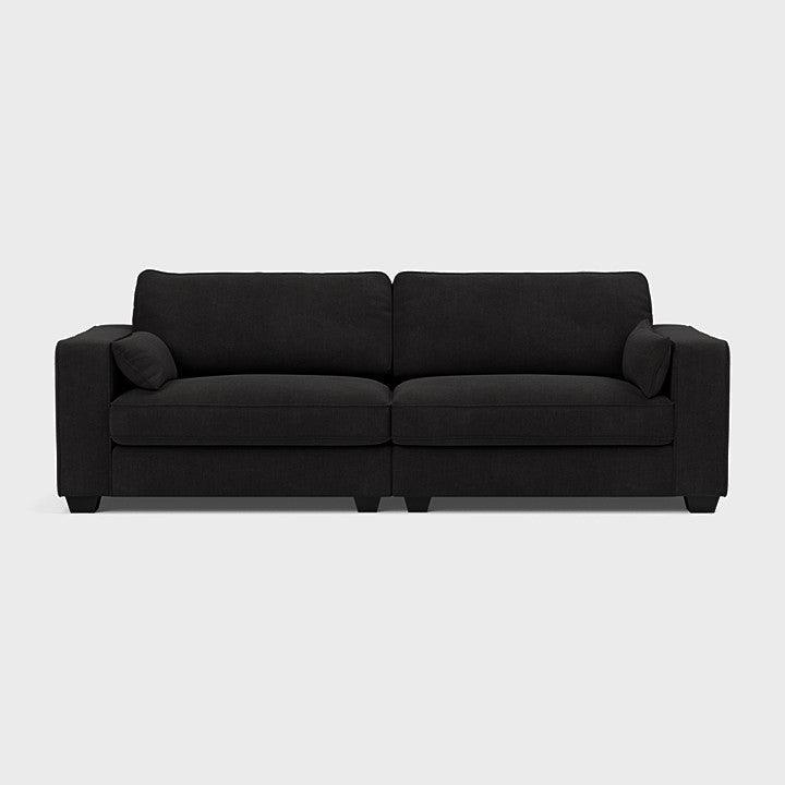 Large modern black fabric sofa with wide armrests and clean lines on a light background