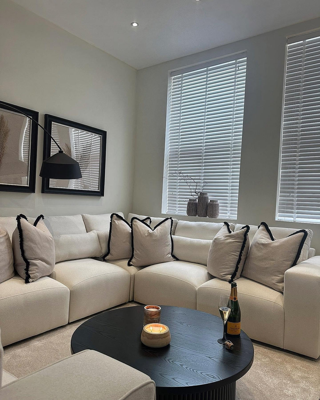 Modern living room with cream corner sofa, black coffee table, and decorative cushions