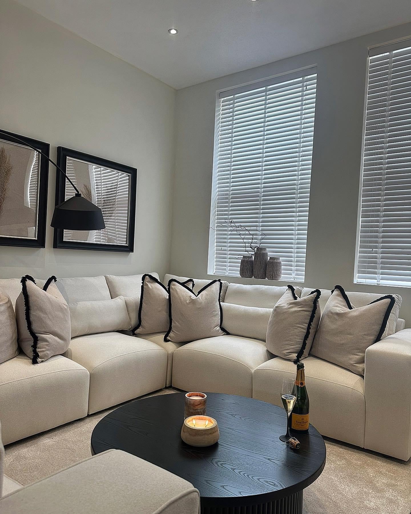 Modern living room with cream corner sofa, black coffee table, and decorative cushions