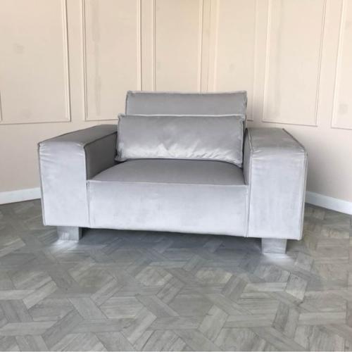 Modern grey velvet armchair with boxy design in a stylish, minimalist living room setting